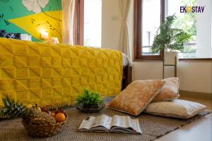a living room with a yellow couch and books on the floor at EKO STAY - Solace Villa I Charming Villa close to Candolim Beach in Marmagao