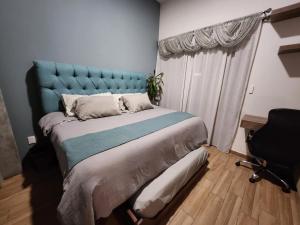 a bedroom with a large bed with a blue headboard at Cozy room in three floor apartment in Mexico City