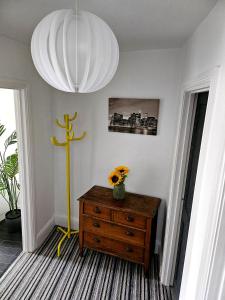 a room with a wooden dresser with a flower in a vase on top at The Penthouse NY Loft Apartment in Barmouth