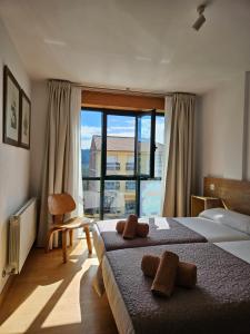 una camera d'albergo con due letti e una grande finestra di PENSION ROSELLA a O Pedrouzo