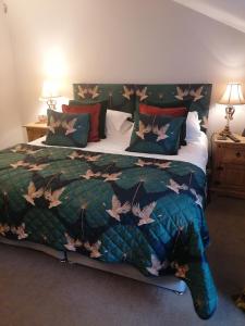 a bedroom with a bed with a green comforter at Kings Head - Riverside, Ravenstonedale in Ravenstonedale