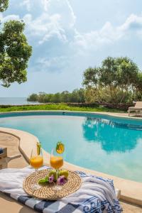 a table with two glasses of juice next to a swimming pool at Mwazaro Beach Lodge in Shimoni