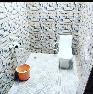 a bathroom with a toilet and a brick wall at Sakleshpur home stay in Sakleshpur