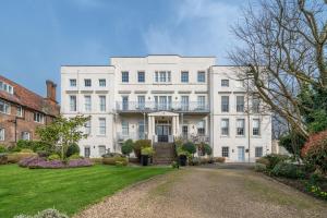 a large white building with a balcony on a yard at Riverside 1 Bed Flat near Hampton Court Palace in East Molesey