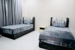 two beds sitting next to each other in a bedroom at MH Homestay No3 for 6ppl at Alor Setar in Alor Setar