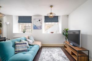 a living room with a blue couch and a tv at Riverside 1 Bed Basement Flat near Hampton Court Palace in East Molesey