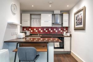 a kitchen with white cabinets and a counter top at Riverside 1 Bed Flat near Hampton Court Palace in East Molesey