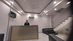 un hombre de pie en un podio en una habitación con escaleras en Hotel Black Eye, en Nueva Delhi