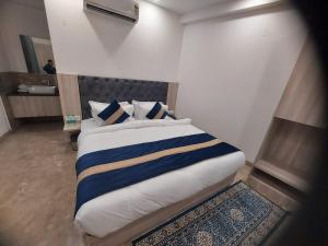 a bedroom with a bed with blue and white sheets and a mirror at Hotel Black Eye in New Delhi