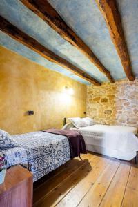 1 dormitorio con 2 camas y pared de piedra en Can Miqueló - casa rural 16 hòstes, en Prat de Comte