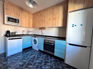 cocina con armarios azules y nevera blanca en Nuevo: Cerca CENTRO , WIFI y Calefacción, en Oviedo
