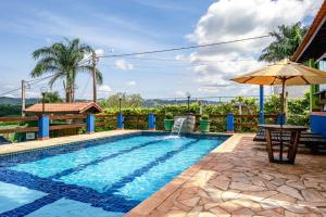 a swimming pool with a table and an umbrella at CHÁCARA TOP, com VISTA das Montanhas, PISCINA, PET FRIENDLY,, ESTACIONAMENTO ,Wi-Fi 213 Mbps in Tuiuti