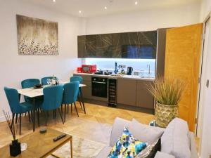 a kitchen and living room with a table and blue chairs at Pass the Keys Large Central Flat Walk To City Centre In 5 Mins in Manchester