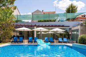 een zwembad met blauwe stoelen en parasols bij Apartments Keti in Splitska