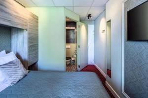 een slaapkamer met een bed en een flatscreen-tv bij Hotel Atlantis Amsterdam in Amsterdam