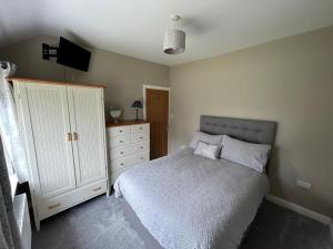 a bedroom with a bed and a dresser at Kerry Wish Cottage - Valentia Island in Knights Town +5 photos