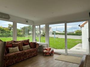 a living room with a couch and large windows at Kerry Wish Cottage - Valentia Island in Knights Town