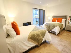 een slaapkamer met 2 bedden en oranje kussens bij Pass the Keys Central 3 Bed Flat 8 Min Walk To City Centre in Manchester