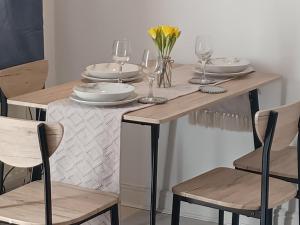 a wooden table with plates and wine glasses on it at Q Flat Skyview Spacious in Bradford