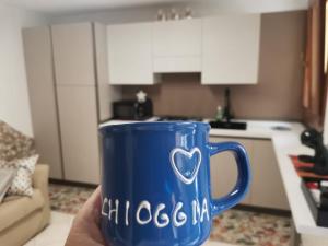 una mano sosteniendo una taza azul con un corazón en ella en KOMI HOUSE, en Sottomarina