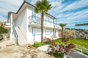 a white house with palm trees in front of it at Apartments Marija 1000 in Rabac