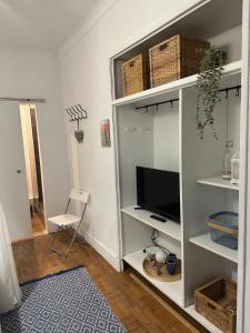 a living room with a white book shelf with a tv at Alojamentos Vista Mar-Luisa Todi in Setúbal