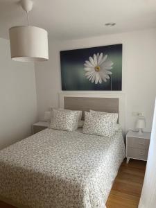 リベイラにあるApartamento Playa de Corosoのベッドルーム1室(花の絵が飾られたベッド1台付)
