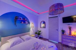 a bedroom with a white bed with a pink lighting at La Quintinha / détente et évasion in Fondettes