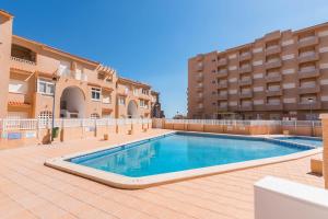 a swimming pool in front of a building at URBANIZACIÓN COPACABANA - La Manga del Mar Menor KM2 - Vistas a Mediterráneo Dormitorio doble y sofá-cama in La Manga del Mar Menor