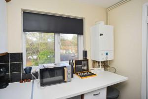 a kitchen with a microwave on a counter with a window at London's Calling You! 2 Bed Lovely Home Sleeps 1-5! in Thamesmead