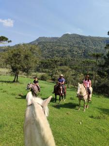 un grupo de personas montando caballos en un campo en Pousada Vale da Imbuia chalé para temporada en Urubici