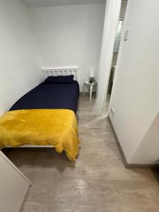 ein Schlafzimmer mit einem Bett mit einer gelben Decke in der Unterkunft Single ensuite room in London