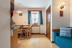 a kitchen and dining room with a table and a blue couch at Agriturismo El Cirum Pelmo in Livinallongo del Col di Lana