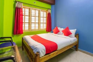 a bedroom with a bed with red and green walls at OYO Flagship 68124 Shangri-la Hotel in Kushālnagar