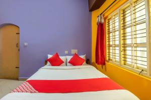a bedroom with a bed with red and white pillows at OYO Flagship 68124 Shangri-la Hotel in Kushālnagar