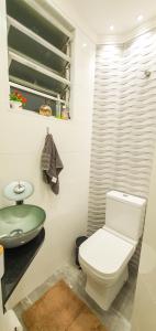 a bathroom with a white toilet and a sink at Santos Gonzaga - Vista mar & localização perfeita in Santos
