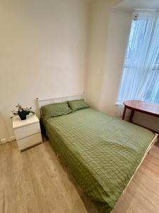 a bedroom with a bed and a table and a window at RELAKS LETTINGS in London