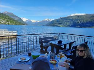a woman sitting at a table on a deck with a view of a lake at Fjord Paradise Stryn in Stryn