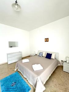 a white bedroom with a large bed with blue rugs at Lenny House alloggio privato in Noci