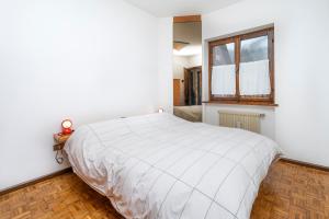 a white bedroom with a bed and a window at Zoncolan Mountain Lodge in Ravascletto