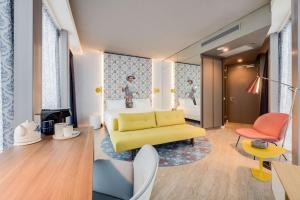 Habitación de hotel con sofá amarillo y dormitorio en nhow Amsterdam Rai en Ámsterdam