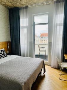 1 Schlafzimmer mit einem Bett und einem Balkon mit einem Stuhl in der Unterkunft Hotel La Grande Cloche in Brüssel