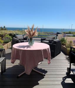 a pink table with a vase of flowers on a deck at Appartement rénové dans résidence de vacances proche océan Les Sables in Les Sables-dʼOlonne