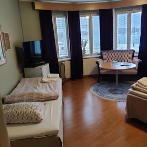a room with two beds and a table and a couch at Hotelli Merikotka in Kotka