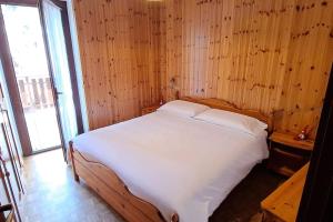 1 dormitorio con 1 cama blanca en una pared de madera en Appartamento Cialuzin, en Pieve di Cadore