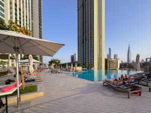 a pool with people laying on lounge chairs next to a building at WORLD CLASS 2BR with Downtown View in Dubai