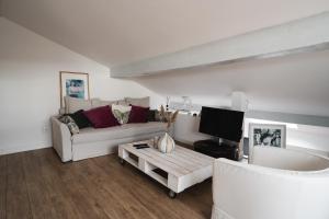 a white living room with a couch and a tv at Terrasse tropezienne in La Ciotat
