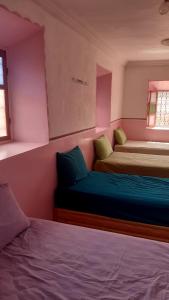 twee bedden in een kamer met roze muren bij Gîte Ait Bouguemez in Azilal