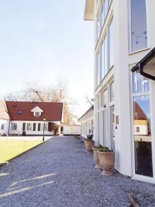 une allée entre deux bâtiments blancs avec des plantes en pot dans l'établissement Elisefarm, à Fogdarp