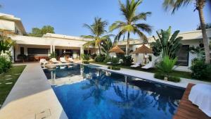 a swimming pool in front of a house with palm trees at Côté Jardin in Somone